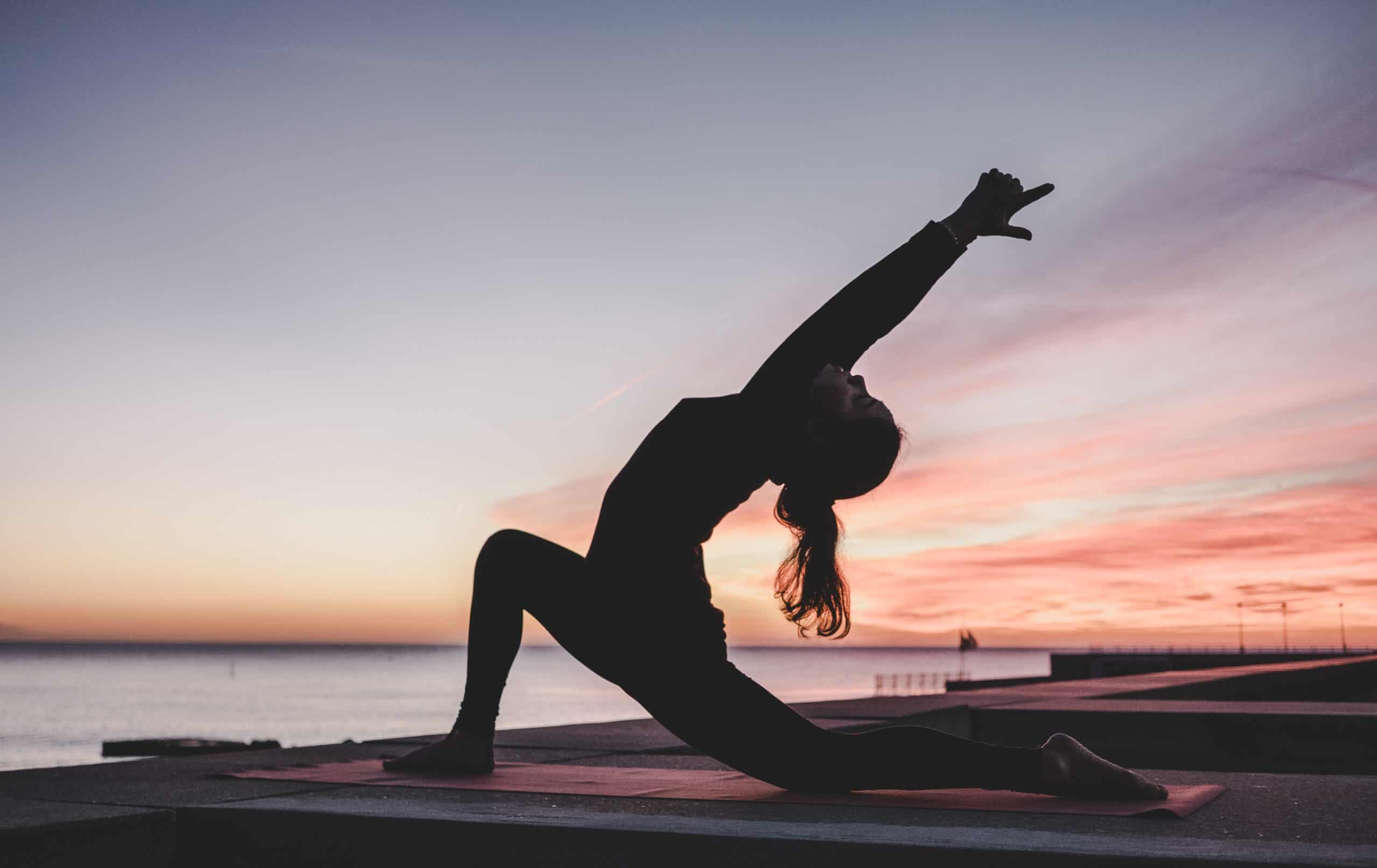 mind body fitness - woman practising yoga at sunrise